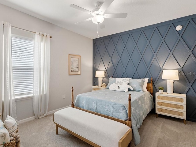 bedroom with an accent wall, carpet, baseboards, and a ceiling fan