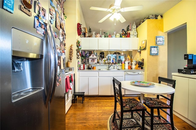 kitchen with stainless steel fridge, white cabinetry, a sink, and wood finished floors