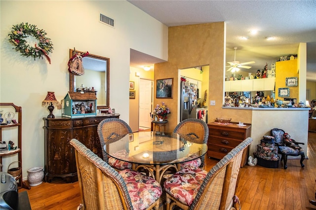 dining room with a ceiling fan, visible vents, and hardwood / wood-style floors