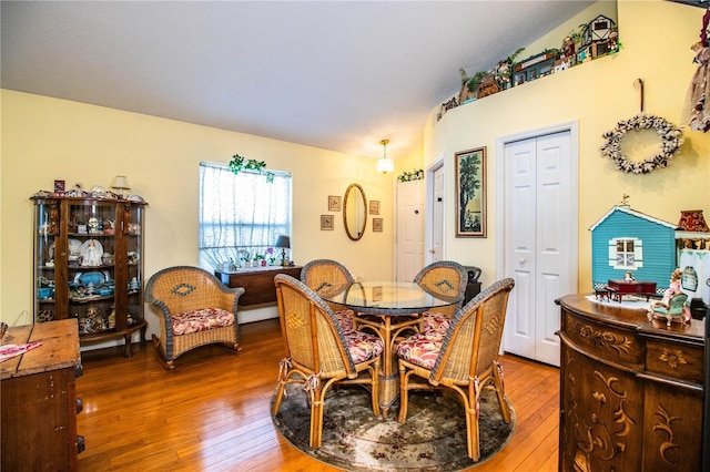 dining area with vaulted ceiling and hardwood / wood-style floors