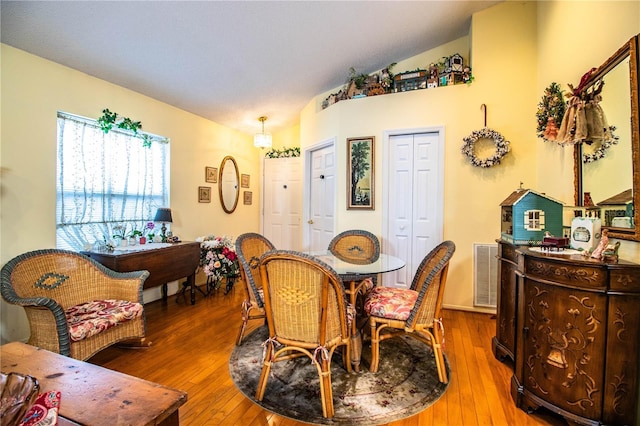 dining room featuring lofted ceiling, hardwood / wood-style floors, and visible vents