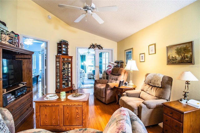 living area with lofted ceiling, hardwood / wood-style floors, a textured ceiling, and a ceiling fan