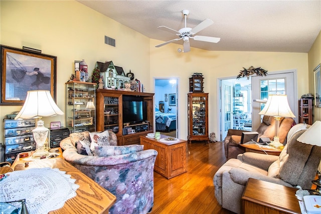 living room featuring light wood finished floors, visible vents, a ceiling fan, lofted ceiling, and a textured ceiling