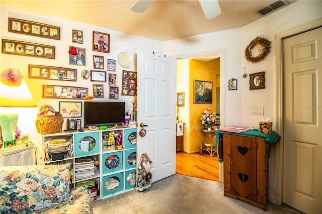 playroom featuring ceiling fan, carpet floors, a textured ceiling, and visible vents