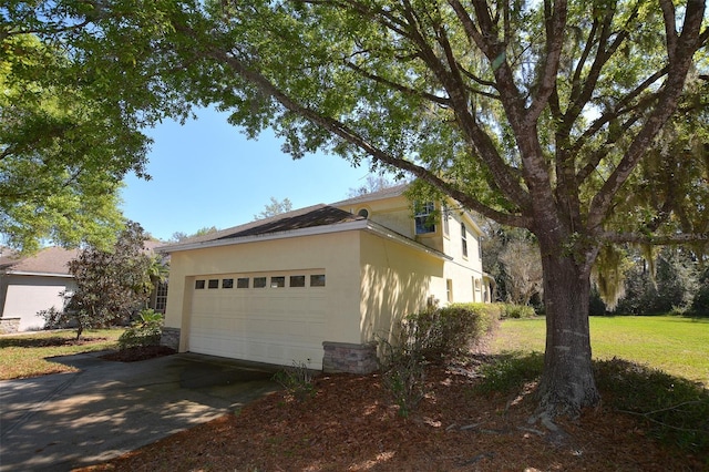 view of side of home with stone siding, an attached garage, driveway, and stucco siding