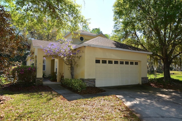 view of front of property with an attached garage, stone siding, concrete driveway, roof with shingles, and stucco siding