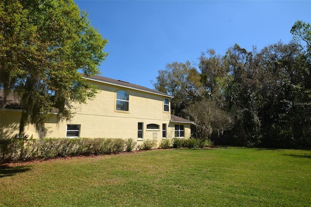 rear view of property with a lawn and stucco siding