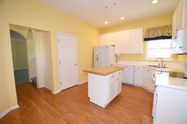 kitchen featuring white appliances, light wood-style flooring, white cabinetry, and a sink