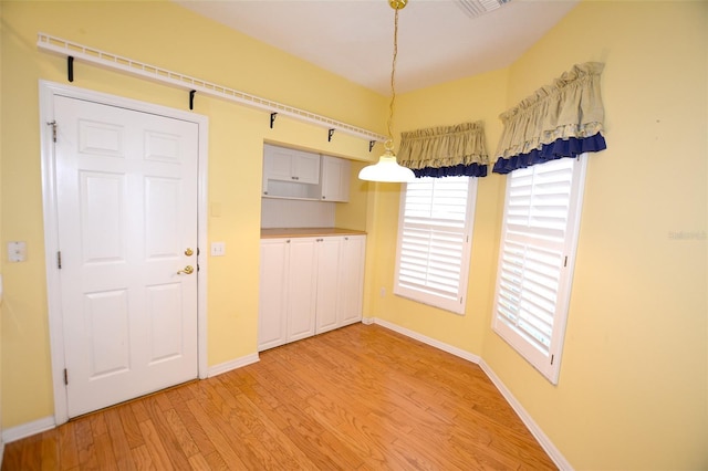 unfurnished dining area featuring light wood finished floors, plenty of natural light, and baseboards