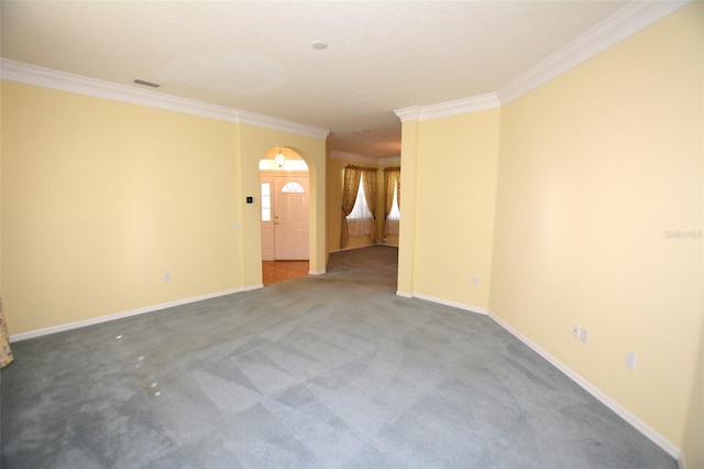 empty room featuring ornamental molding, carpet, visible vents, and baseboards