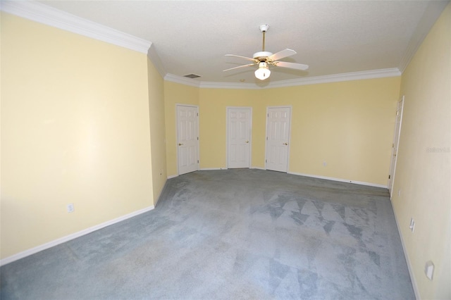 carpeted spare room with ornamental molding, visible vents, baseboards, and a ceiling fan