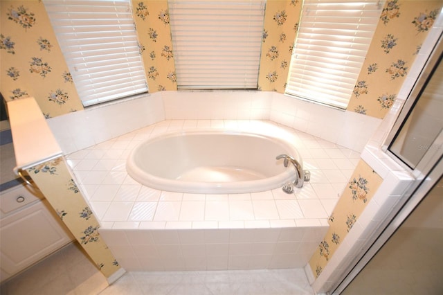 bathroom with wallpapered walls and a bath