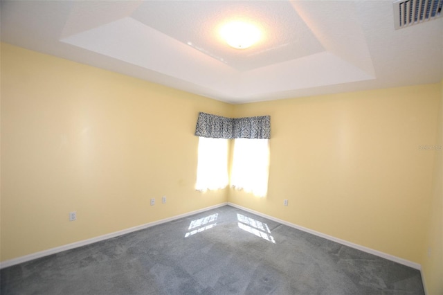 unfurnished room featuring a tray ceiling, visible vents, and baseboards