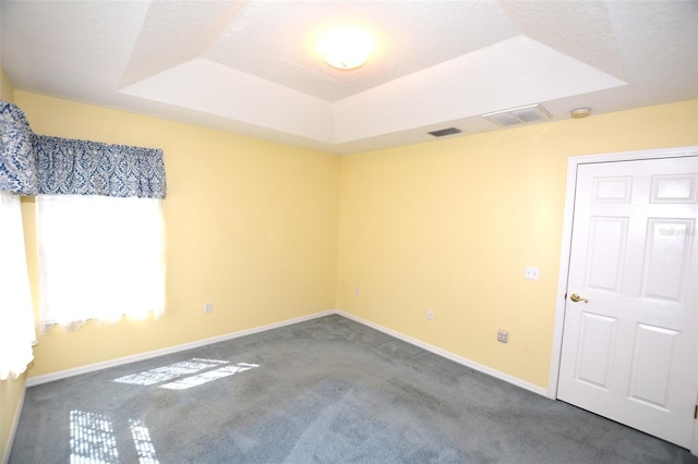 empty room featuring carpet floors, baseboards, visible vents, and a raised ceiling