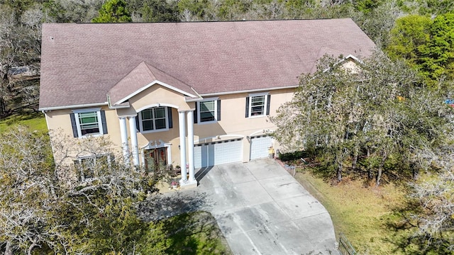 view of front facade with a garage, concrete driveway, and stucco siding