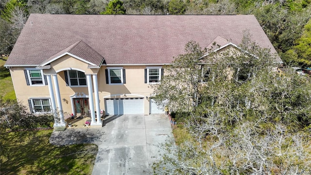 view of front of house with driveway, roof with shingles, and stucco siding