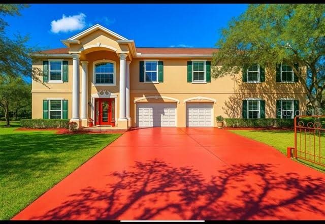 11175 Hyde St, Weeki Wachee, FL 34614 - neoclassical home with stucco siding, concrete driveway, a front yard, and an attached garage