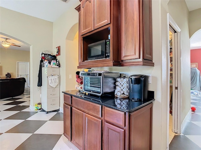 11175 Hyde St, Weeki Wachee, FL 34614 - kitchen with arched walkways, black microwave, light flooring, and a ceiling fan