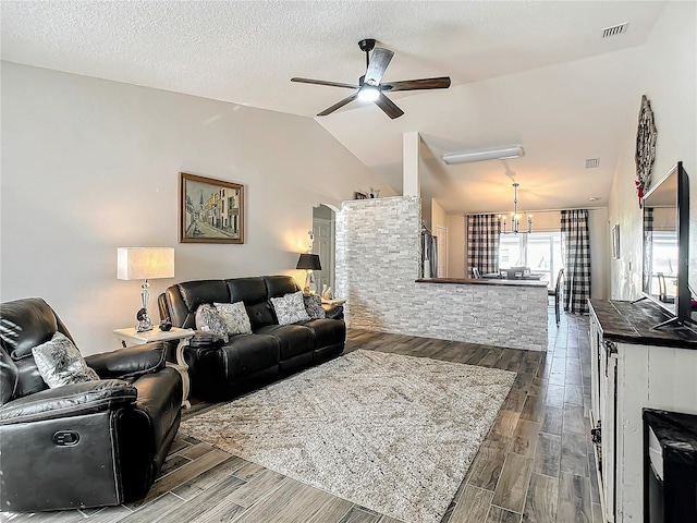 living room with visible vents, dark wood-type flooring, vaulted ceiling, a textured ceiling, and ceiling fan with notable chandelier