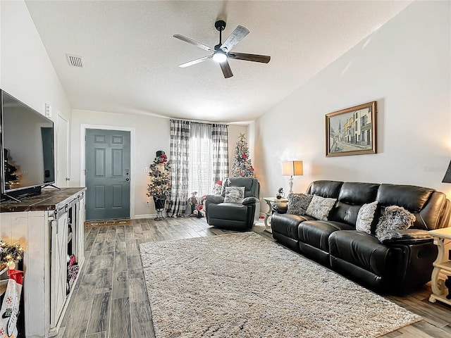 living room featuring vaulted ceiling, wood finished floors, visible vents, and ceiling fan