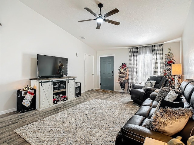 living room with vaulted ceiling, visible vents, a ceiling fan, and wood finished floors