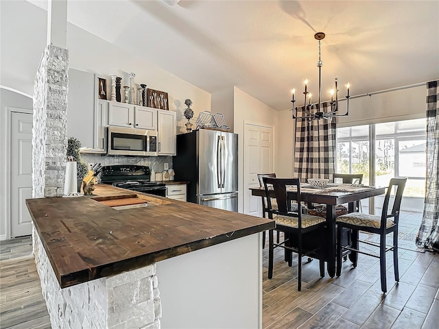 kitchen with tasteful backsplash, a chandelier, butcher block counters, lofted ceiling, and stainless steel appliances