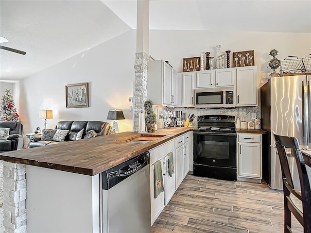 kitchen featuring wood finish floors, wooden counters, appliances with stainless steel finishes, and open floor plan