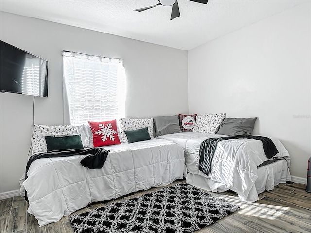 bedroom featuring baseboards, a textured ceiling, ceiling fan, and wood finished floors