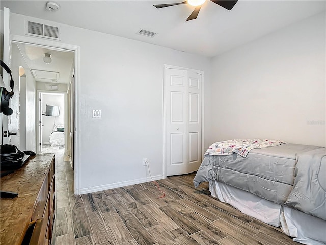 bedroom featuring wood finished floors, visible vents, and a closet