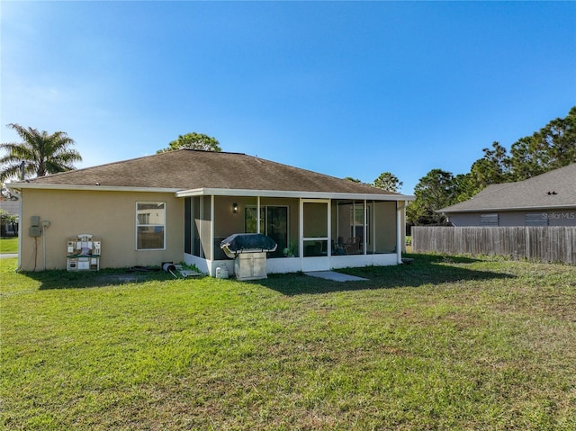 back of house featuring stucco siding, fence, a lawn, and a sunroom