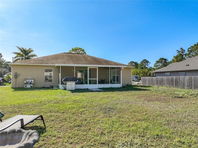 back of property featuring stucco siding, a lawn, fence, and a sunroom