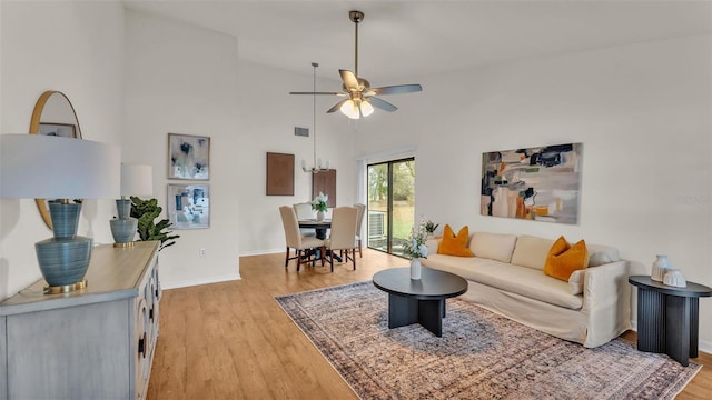 living room with visible vents, baseboards, light wood-style flooring, ceiling fan, and high vaulted ceiling