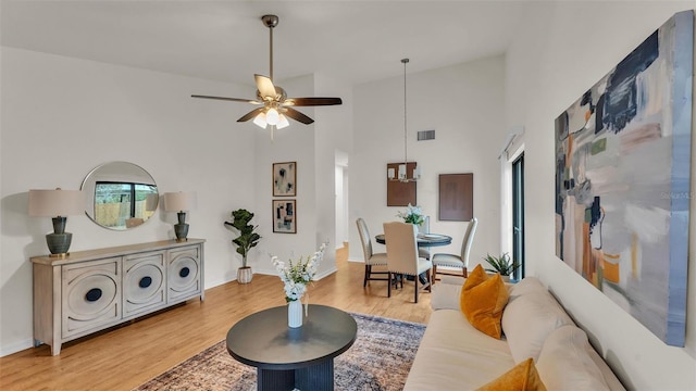 living area featuring baseboards, visible vents, a high ceiling, and wood finished floors