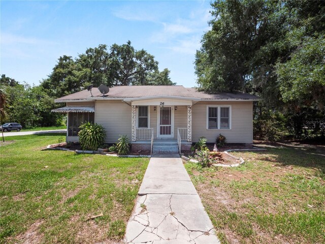 ranch-style home featuring covered porch and a front lawn