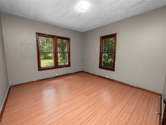 empty room with a textured ceiling, wood finished floors, and baseboards