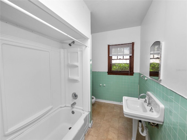 full bath featuring wainscoting, toilet, a sink, washtub / shower combination, and tile walls