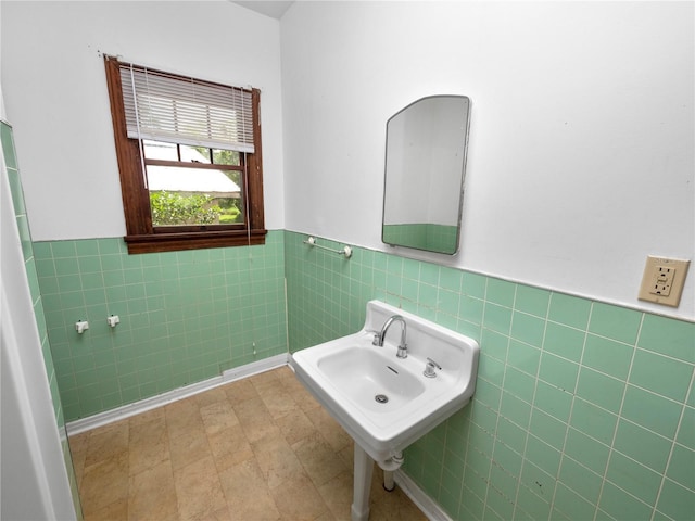 bathroom with a sink, a wainscoted wall, and tile walls