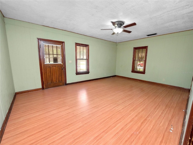 unfurnished room featuring a textured ceiling, ceiling fan, light wood-type flooring, and baseboards