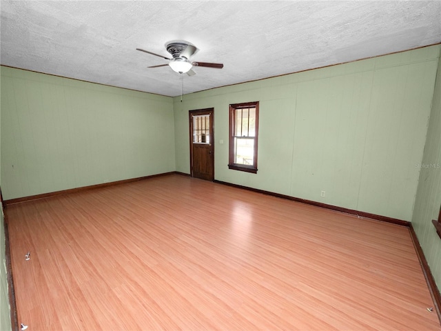 unfurnished room featuring baseboards, a textured ceiling, a ceiling fan, and wood finished floors