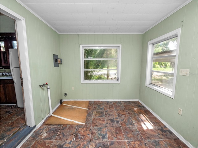 unfurnished room featuring crown molding, stone finish floor, and baseboards