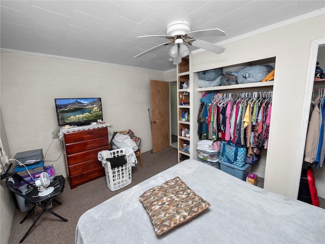 bedroom with concrete block wall, ceiling fan, crown molding, carpet flooring, and a closet