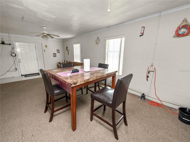 dining space featuring light colored carpet, a ceiling fan, and crown molding