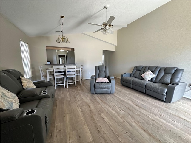 living room with visible vents, a ceiling fan, vaulted ceiling, a textured ceiling, and wood finished floors