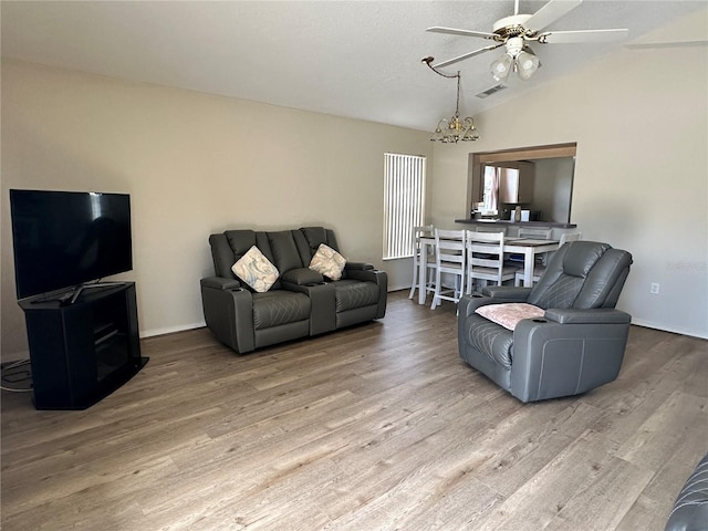 living area featuring lofted ceiling, visible vents, ceiling fan, wood finished floors, and baseboards