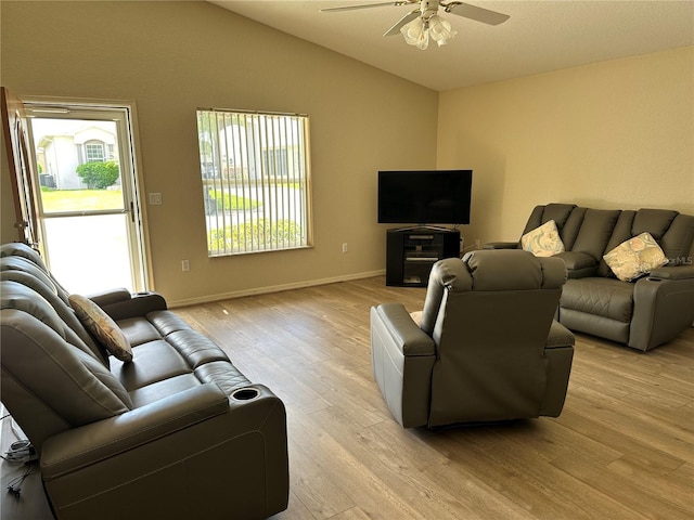 living room with lofted ceiling, light wood finished floors, a ceiling fan, and baseboards