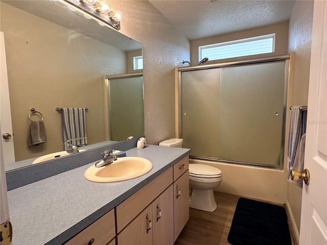 full bathroom with a textured ceiling, a textured wall, toilet, wood finished floors, and vanity