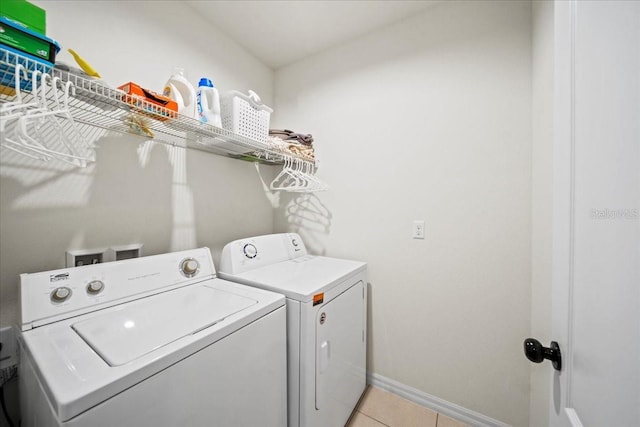 laundry area featuring baseboards, laundry area, light tile patterned flooring, and washer and dryer