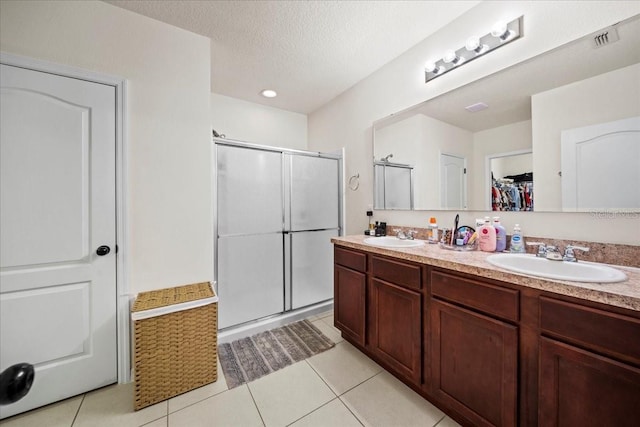 full bathroom with a stall shower, a sink, and a textured ceiling