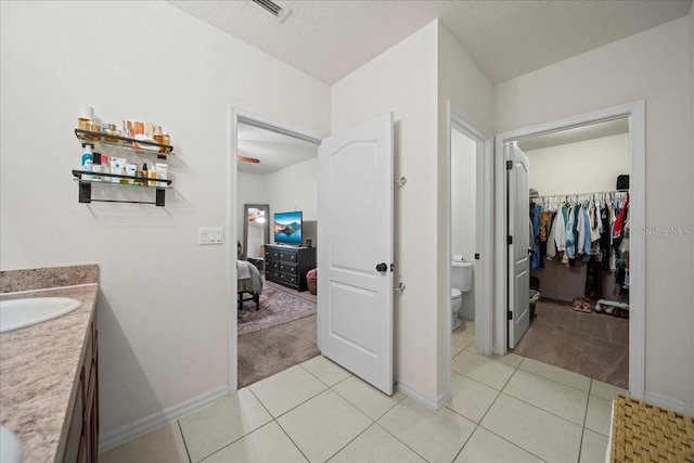 ensuite bathroom with toilet, ensuite bath, tile patterned flooring, and vanity