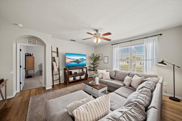 living room with ceiling fan, wood finished floors, and visible vents